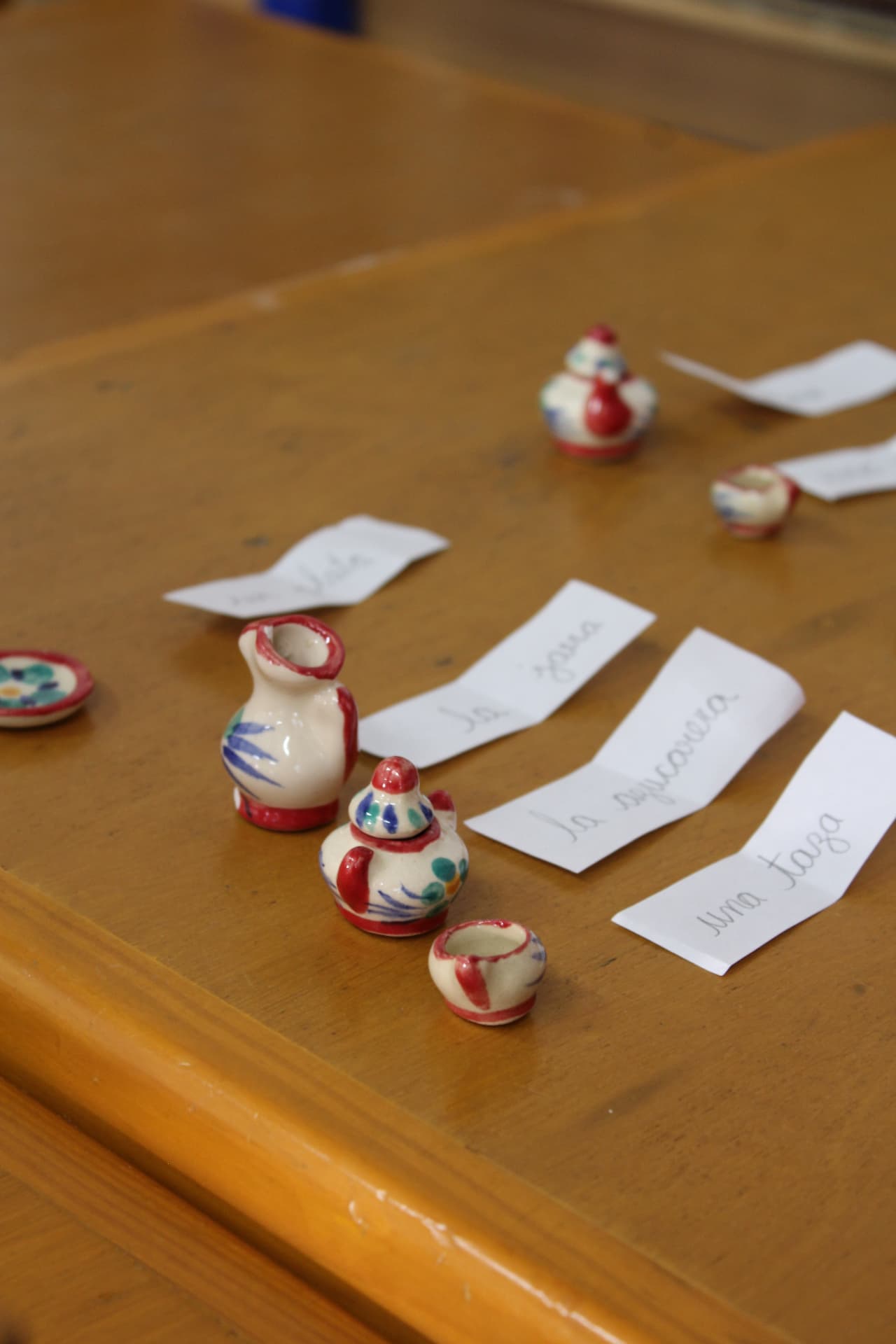 Miniaturas de cerámica con etiquetas escritas a mano para ejercicios de lenguaje